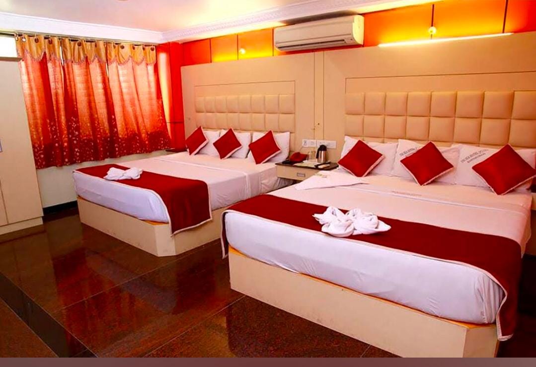 Family room at Gujarat Bhavan Kanyakumari with two large beds and red furnishings