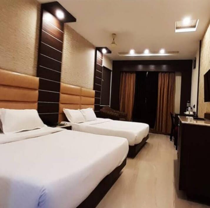 Guest room at Gujarat Bhavan Kanyakumari with two beds and wooden headboards