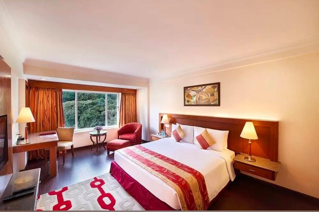 Guest room at Gujarat Bhavan Kanyakumari with a double bed, desk and armchair